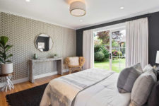 07 The bedroom is done with a printed wallpaper wall, a glass door to the garden and some stylish furniture