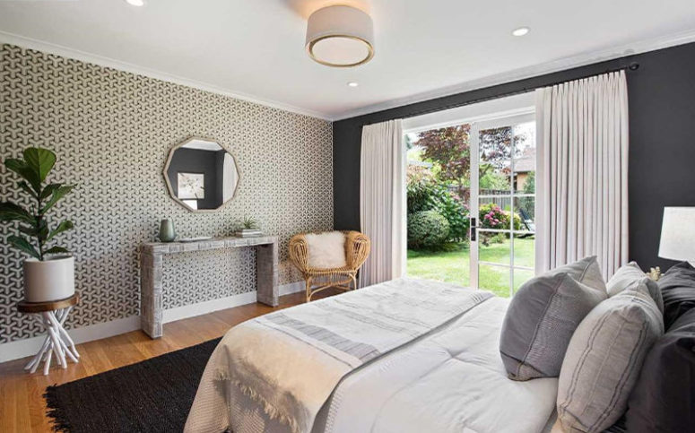 The bedroom is done with a printed wallpaper wall, a glass door to the garden and some stylish furniture The bedroom is done with a printed wallpaper wall, a glass door to the garden and some stylish furniture