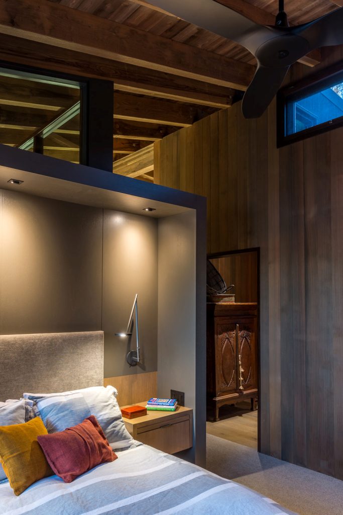 The bedroom shows off a niche with a bed and floating nightstands with sconces to make sleeping cozier