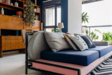 07 The storage unit is a mid-century wooden one, and there’s a desk there, a bright sofa is a centerpiece here