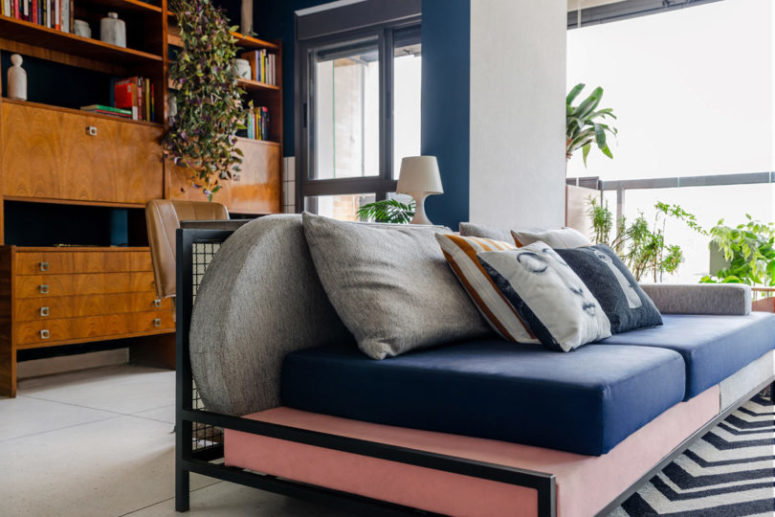 The storage unit is a mid-century wooden one, and there's a desk there, a bright sofa is a centerpiece here