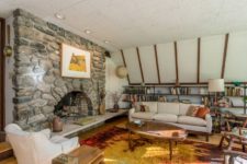 07 There’s another living room with white walls, a stone fireplace and comfy mid-century modern furniture
