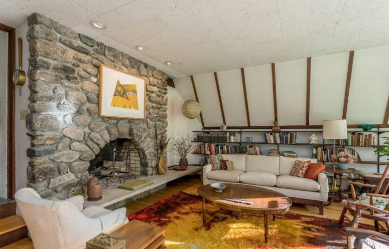 There's another living room with white walls, a stone fireplace and comfy mid century modern furniture There's another living room with white walls, a stone fireplace and comfy mid-century modern furniture