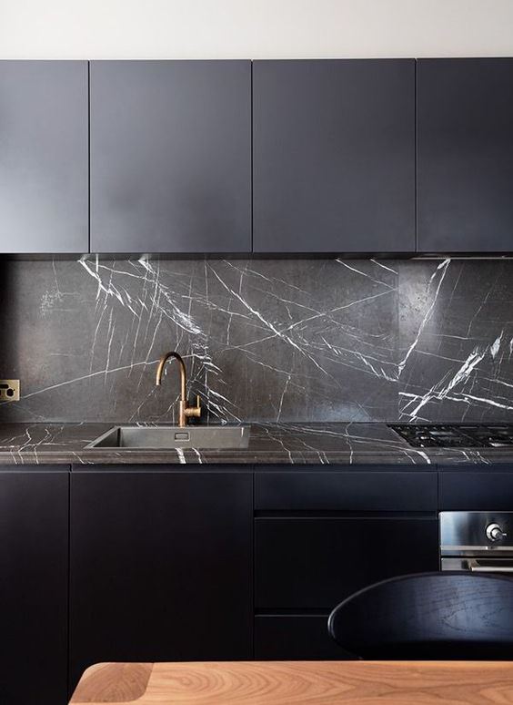 a minimalist midnight blue kitchen with a black marble backsplash and brass touches looks super cool