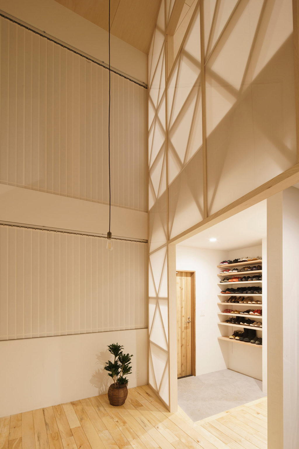 The entryway is clean and minimal, with open shelves for shoes and a rug