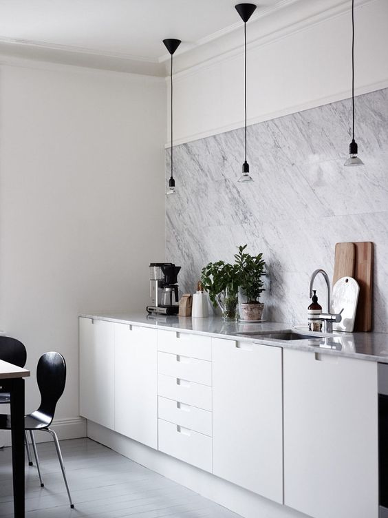 a modern white kitchen with a white marble tile backsplasj and countertops looks chic, elegant and stylish