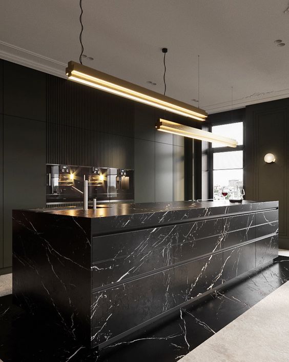 an exquisite black kitchen with plain cabinets and an oversized black marble kitchen island plus touches of gold