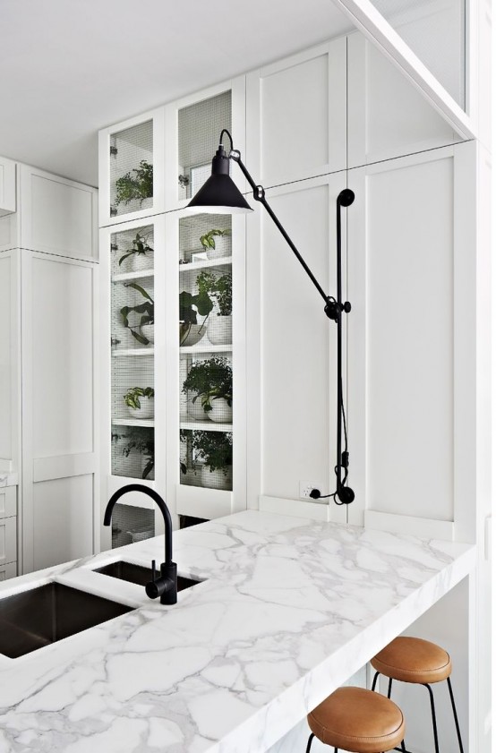 a white vintage kitchen with black touches for more drama and a white kitchen island clad with marble