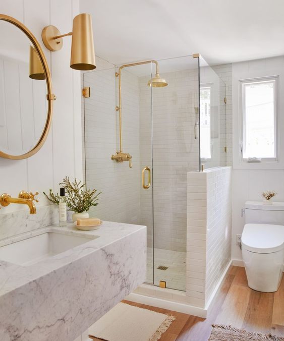 a chic and glam white bathroom with white tiles, a white marble floating sink and touches of gold for a shiny look