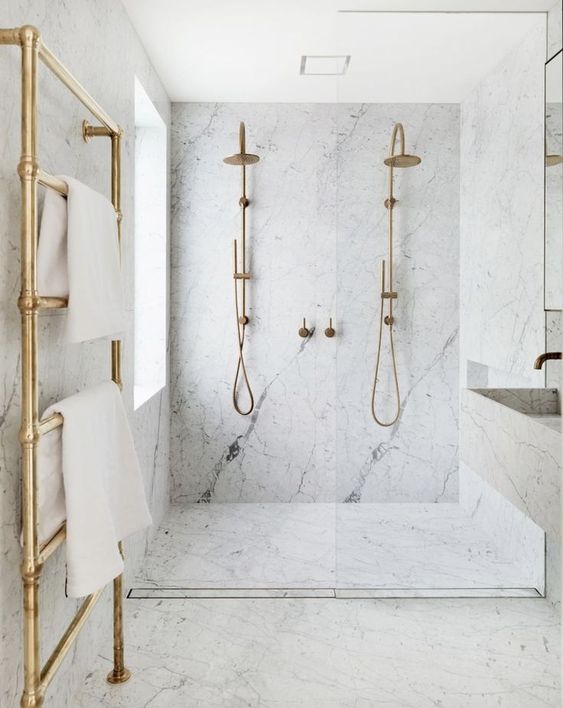 an elegant white marble bathroom with brass and gold touches is pure luxury with a modern feel
