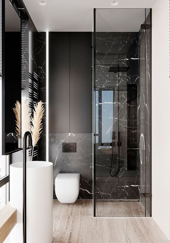 a refined minimalist bathroom with black marble tiles, black matte surfaces and white appliances for a bold look