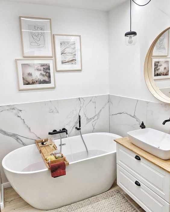 a small contemporary bathroom with a white marble backsplash and white furniture plus a gallery wall