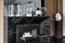 23 a refined space with a black marble fireplace, black leather sotols and a large mirror is wow