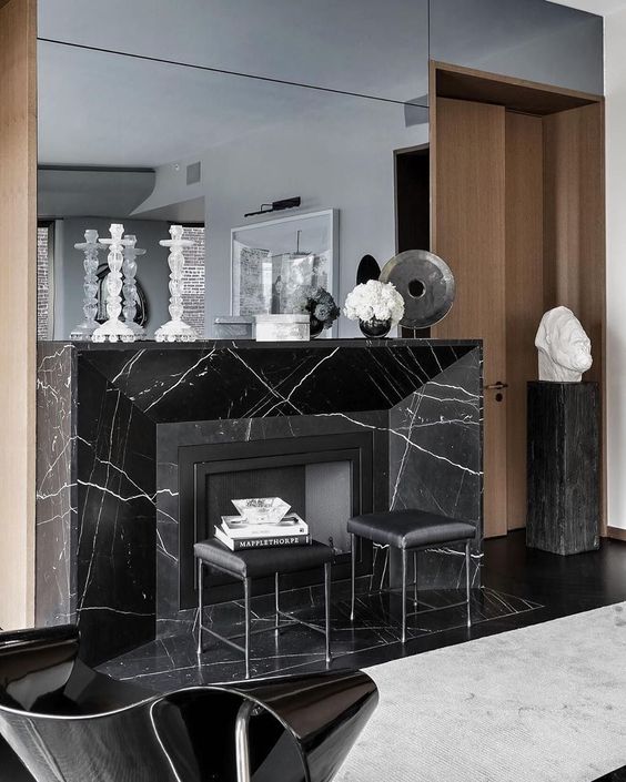 a refined space with a black marble fireplace, black leather sotols and a large mirror is wow