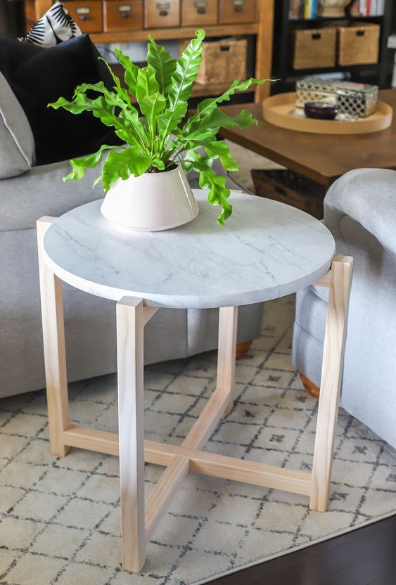 a stylish side table or plant stand with wooden legs and a white marble tabletop is a stylish idea
