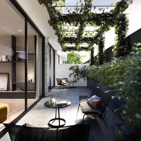 a chic modern patio with a long black planter along the wall, black garden furniture and much greenery climbing up the space