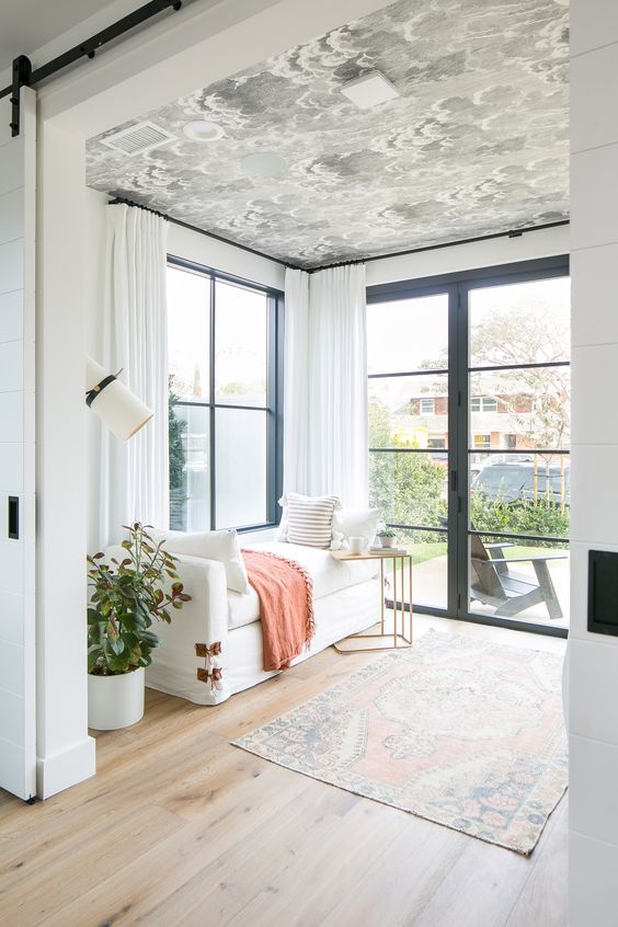 a cool sunroom with a printed wallpaper ceiling that adds pattern to the space and makes it more welcoming and interesting