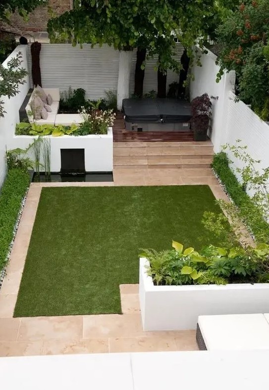 a minimalist townhouse garden with white flower beds with greenery, a tiny pond, a manicured lawn, a sectional sofa and a hot tub