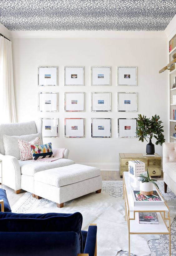 a neutral living room made bolder with a navy chair, a gold sideboard and a wallpaper printed ceiling