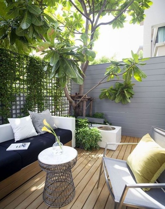 a small modern patio with a storage bench, a metal chair and table and lush greenery here to refresh the space