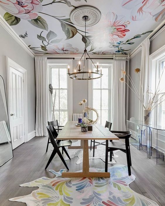 a stylish dining space with a florla wallpaper ceiling that brings pattern and color to the space