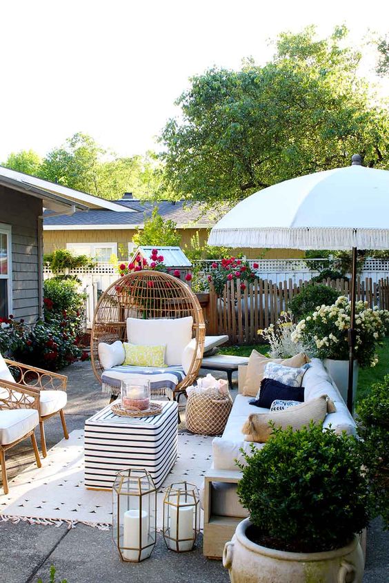 a summer backyard with rattan furniture, candles, potted greenery and bright blooms all around