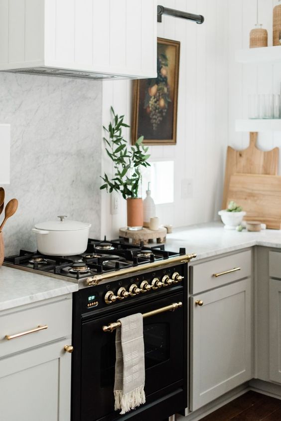 an elegant black cooker and some gold touches add drama and chic to the neutral kitchen with a vintage feel