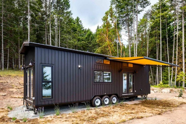 This tiny house on wheels is a stylish home with a black exterior and a spacious interior