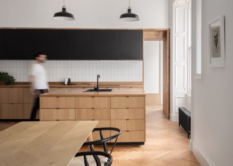 The kitchen is done with light stained cabinets, with a white tile backsplash and matte black uppers The kitchen is done with light stained cabinets, with a white tile backsplash and matte black uppers