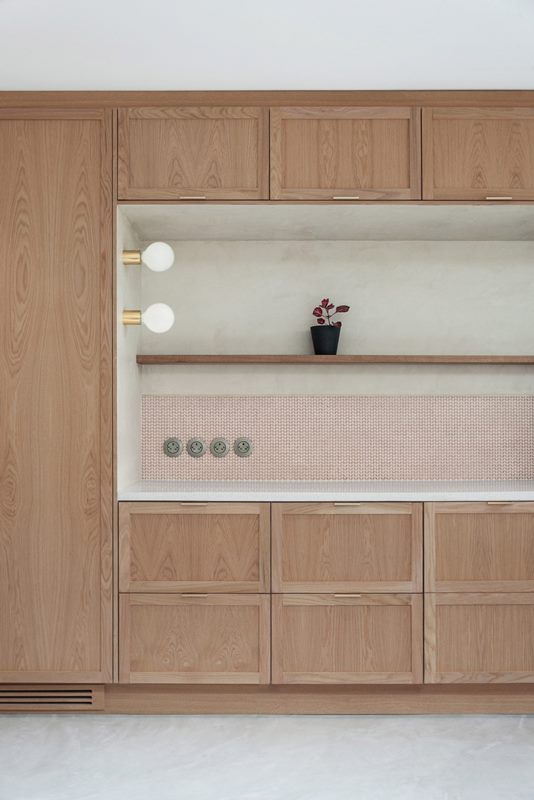 The kitchen is done with light-stained wooden cabinets, a patterned backsplash and built-in lamps