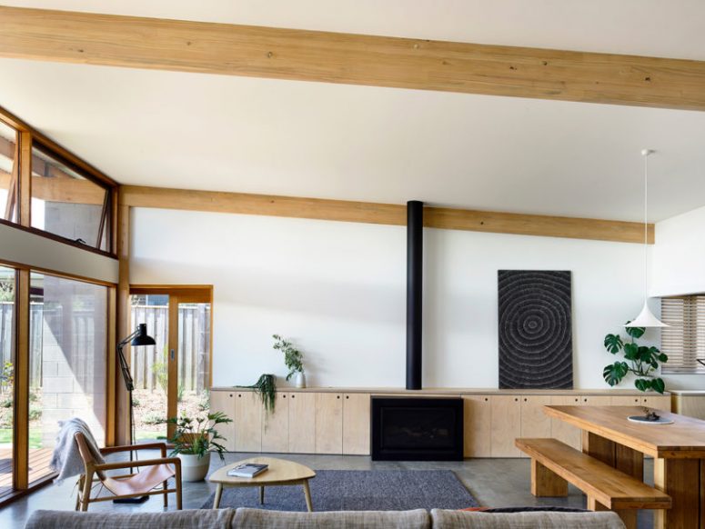 The living room features extensive glazing, plywood cabinets for storage, a fireplace, some comfy furniture and a dining space here The living room features extensive glazing, plywood cabinets for storage, a fireplace, some comfy furniture and a dining space here