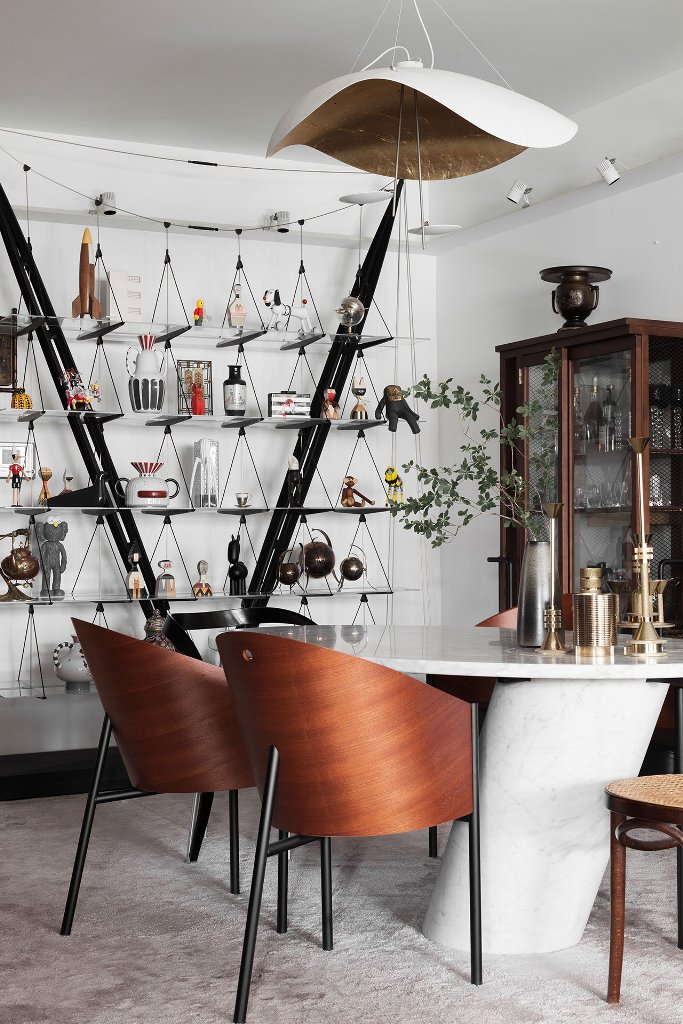 The dining room shows off curved chairs, a marble table and an open storage unit