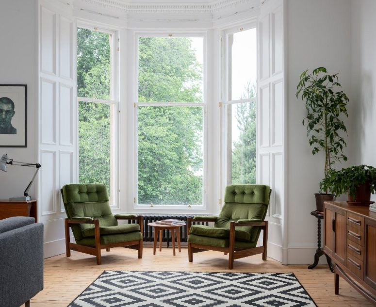There's a bay window with a couple of green chairs, which is a great conversation space or a reading one