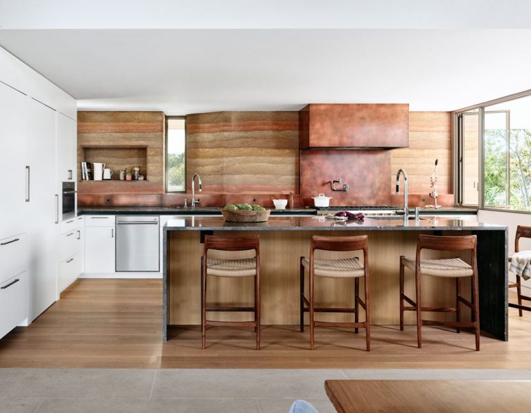 The backspalsh and hood are clad with copper to echo with the fireplace and highlight the color scheme The backspalsh and hood are clad with copper to echo with the fireplace and highlight the color scheme