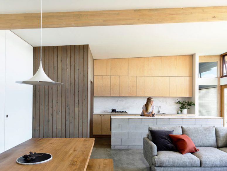 The kitchen is done with plywood cabinets, a marble backsplash and a tiled kitchen island with a stone countertop The kitchen is done with plywood cabinets, a marble backsplash and a tiled kitchen island with a stone countertop