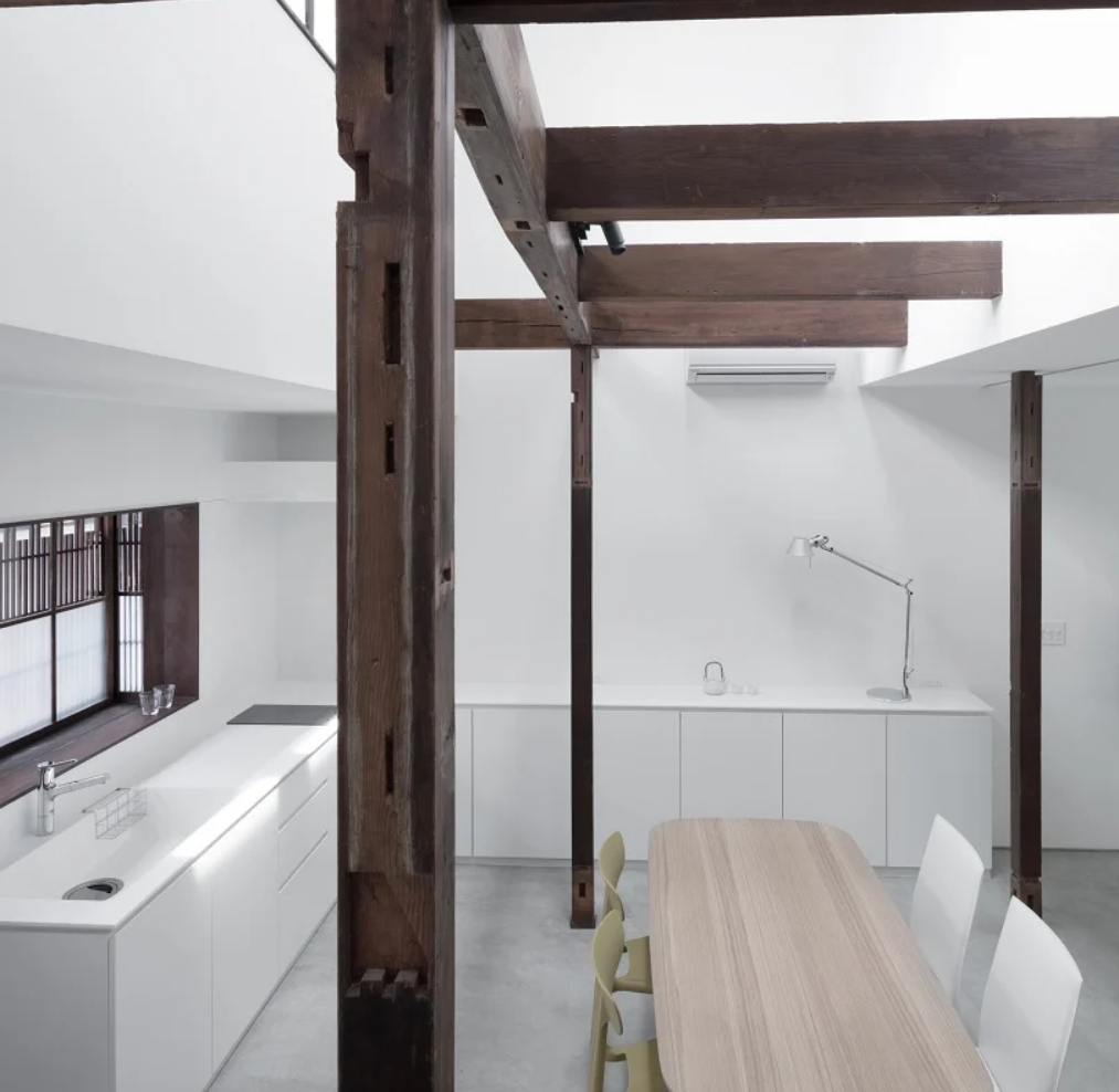 The kitchen is white and minimalist, and the dining space is also here, the original wooden structure adds interest to the space