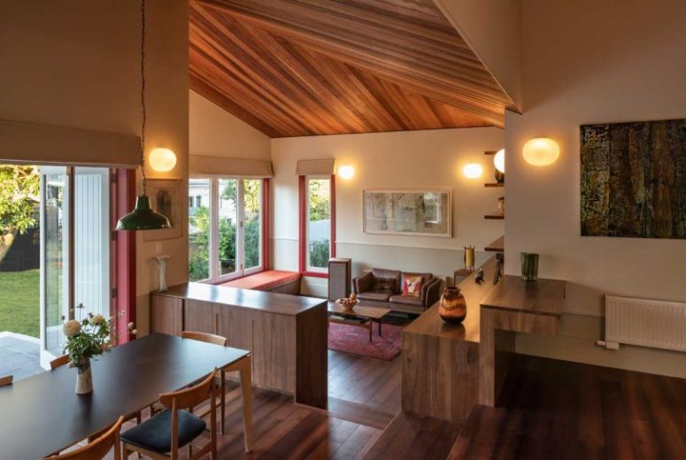 The living room is on a lower level, with a comfy ornage window seat, stylish mid-century modern furniture and lights