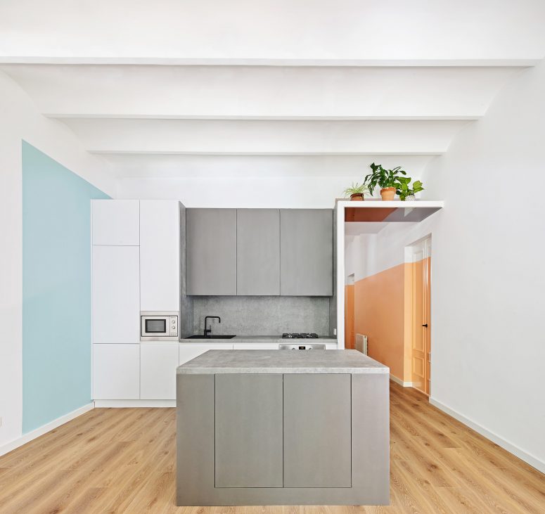 The kitchen also shows off color blocking with graphite grey furniture and a light blue square