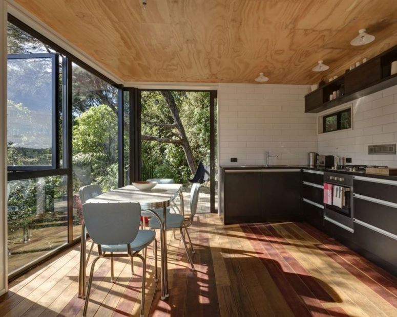The kitchen is small and is done with black cabinets, there's a dining space by the glazed wall here
