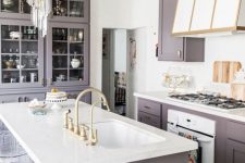 a modern glam kitchen in lilac and white, with gold touches, a chic hood and a modern crystal chandelier over the island