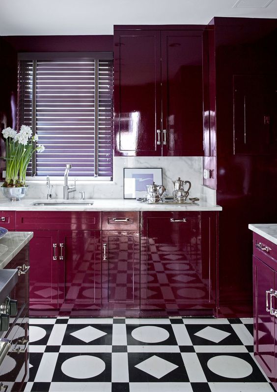 a super bold plum-colored kitchen with white stone countertops and a backsplash and a mosaic tile floor is wow