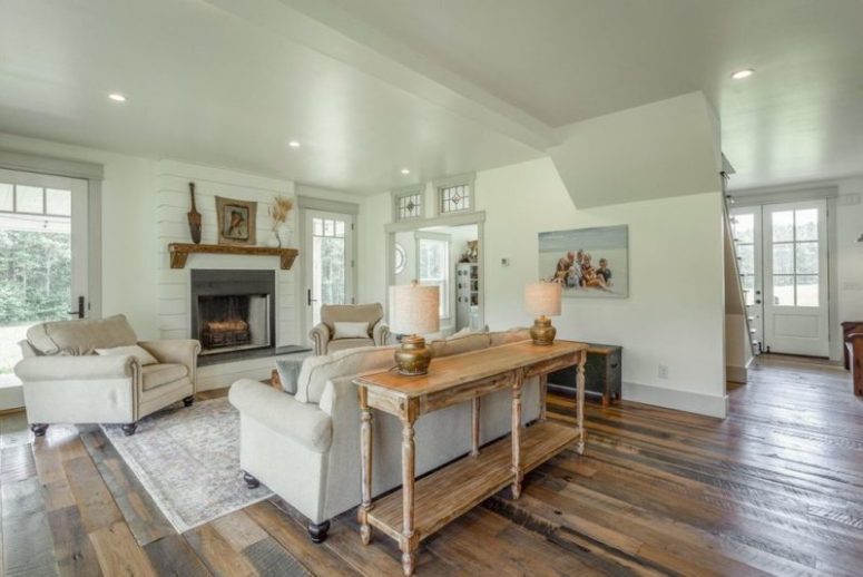 The living room is done in neutrals, with a fireplace, a wooden console table and comfy sitting furniture