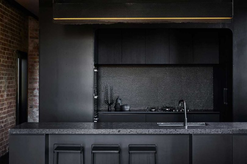 Black fixtures and a penny tile backsplash continue the moody color scheme