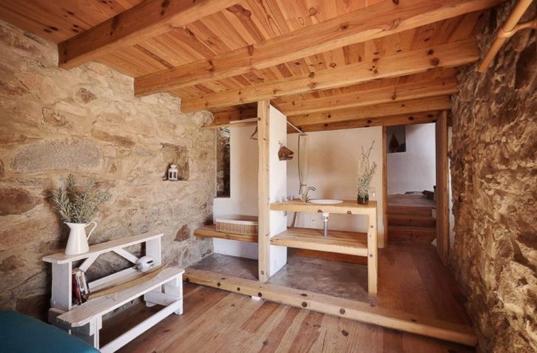 The bathroom is done with wood and stone, there's a vanity with a sink, a basket and a tub