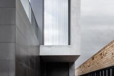 04 The entrance is framed by a black accent wall and a fence which contrast with the light gray exterior walls