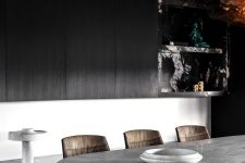 05 The dining room features black sleek cabinets, a marble top table, leather chairs and a black marble slab
