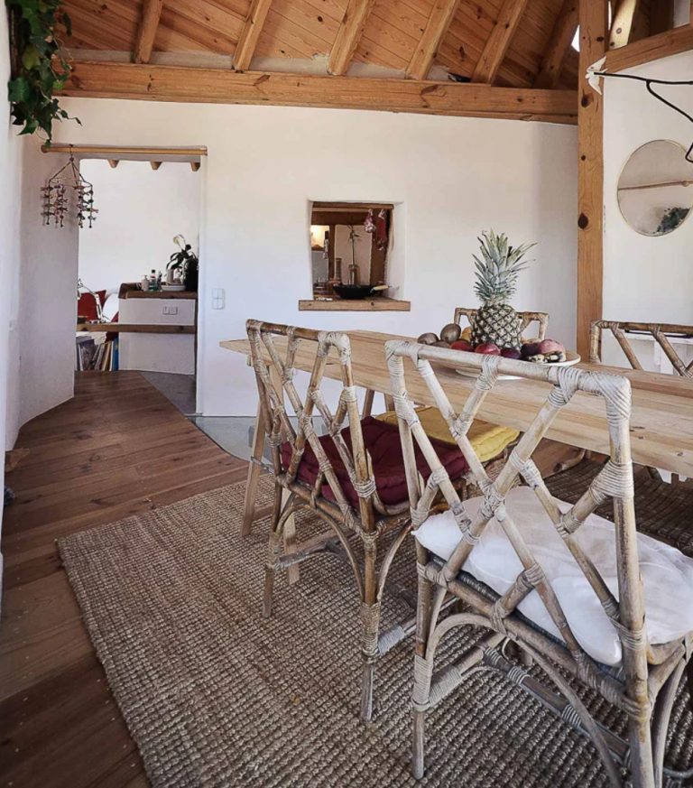 The dining space is done with a wooden table and rattan and twine chairs, there's a window to this space