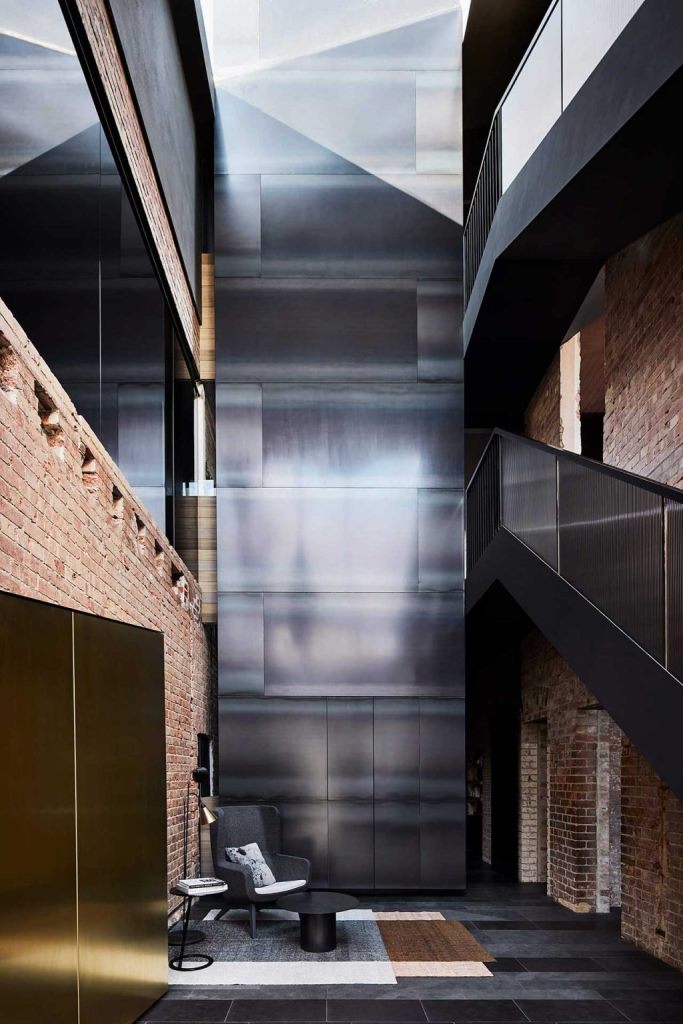 The entryway excites and astonishes with a polished metal wall, chic black furniture and brick walls The entryway excites and astonishes with a polished metal wall, chic black furniture and brick walls