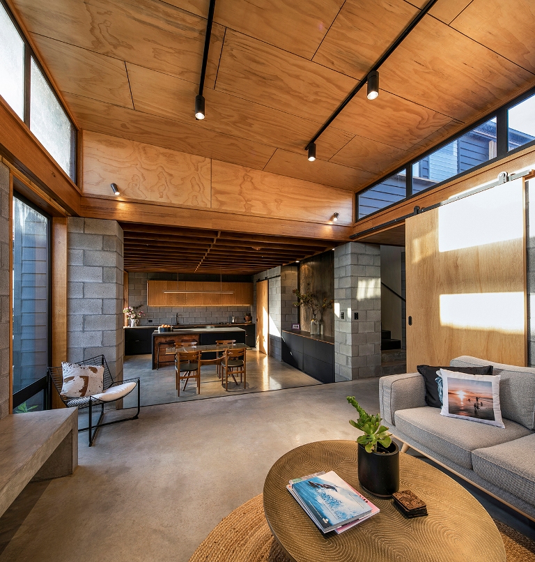 The kitchen opens up to a living room, with neutral comfy furniture and a concrete floor plus glazed walls The kitchen opens up to a living room, with neutral comfy furniture and a concrete floor plus glazed walls