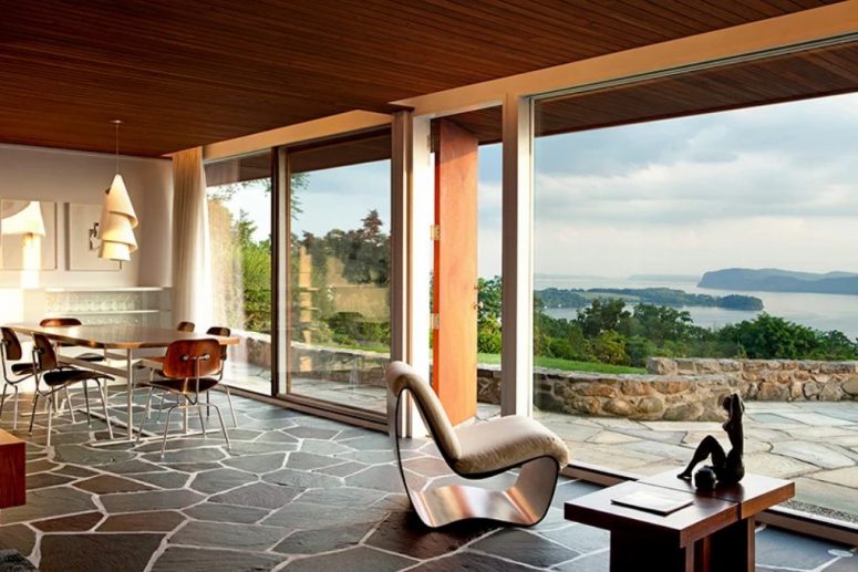 The dining and living room are united into one space with cool furniture, a rock floor and gorgeous river views